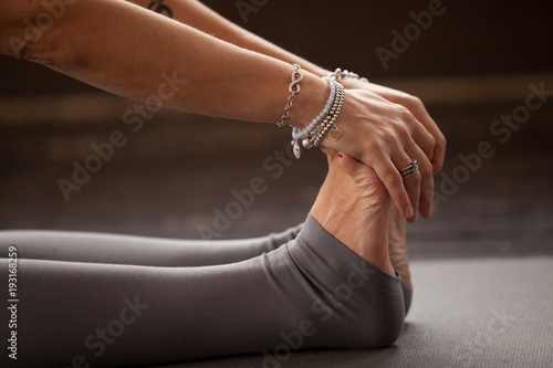 Close up of female feet, yogi woman practicing yoga lesson, stretching in paschimottanasana exercise, Seated forward bend pose, working out, indoor, studio. Healthy lifestyle concept