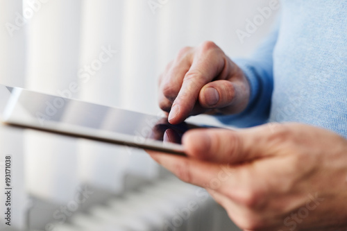 Man working on a digital tablet near a window