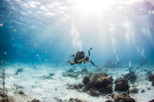Scuba diving on coral reef underwater with rays light background.