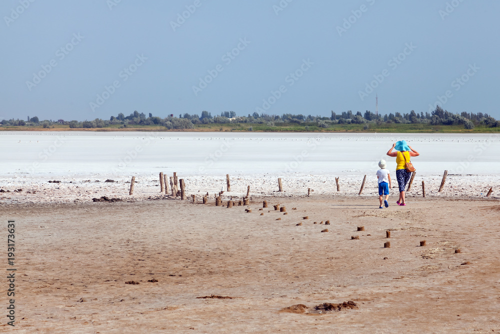 Two tourists among flat plain, steppe, salt, salt lake, heat and sky