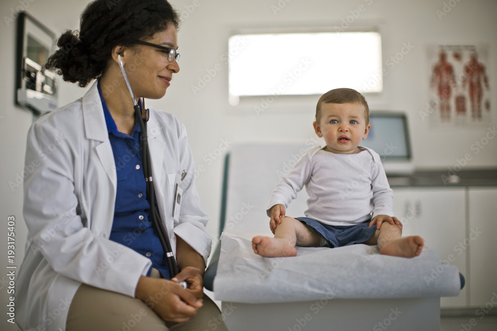 Female doctor looking at baby boy while sitting in hospital Female doctor looking at baby boy while sitting in hospital