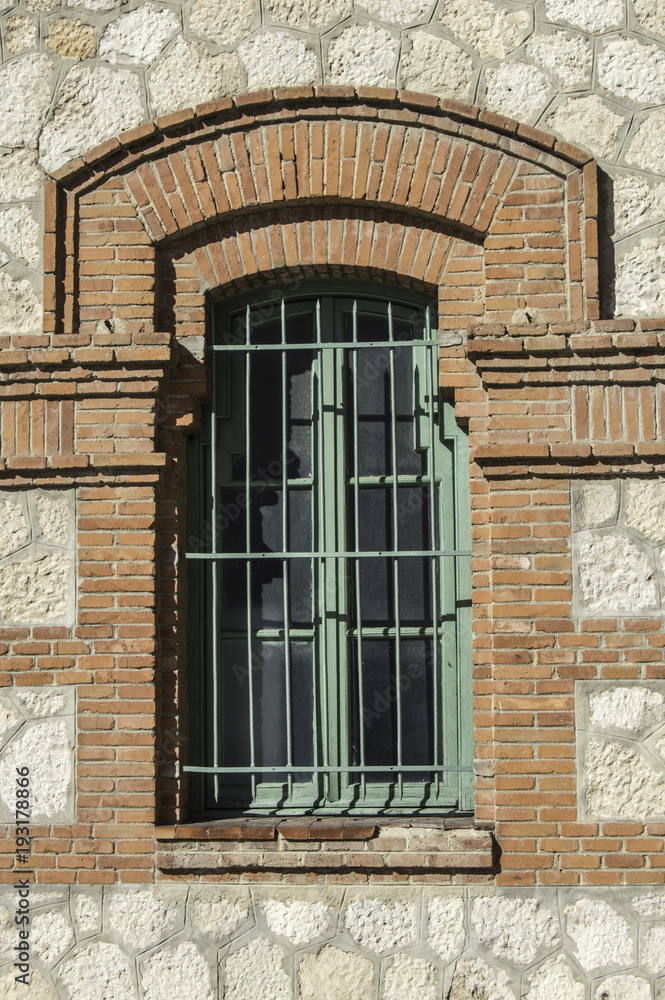 ventana con reja verde y marco de ladrillo.