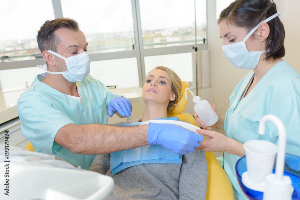 Dentist preparing to treat young lady Dentist preparing to treat young lady