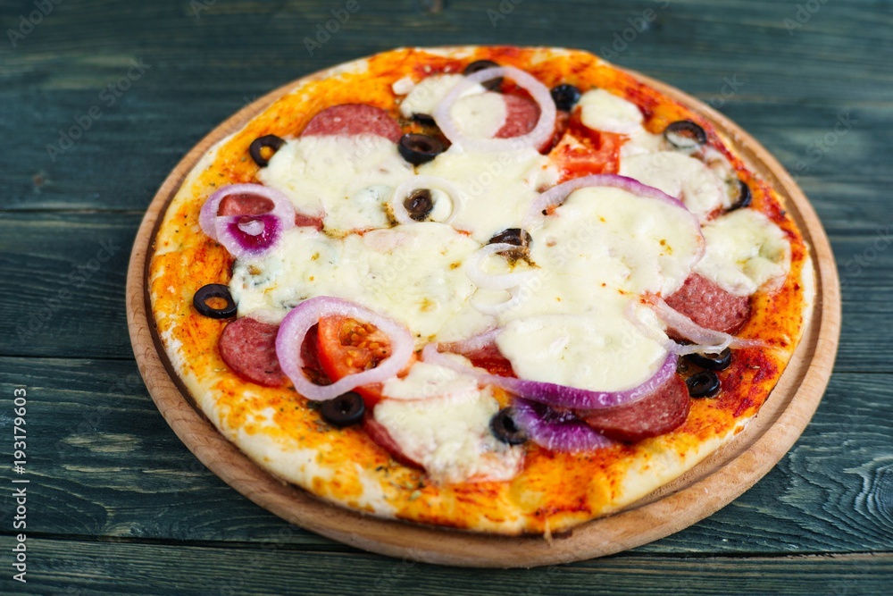 Freshly baked pepperoni pizza with olives on the wooden plate, close up. Italian food Freshly baked pepperoni pizza with olives on the wooden plate, close up. Italian food