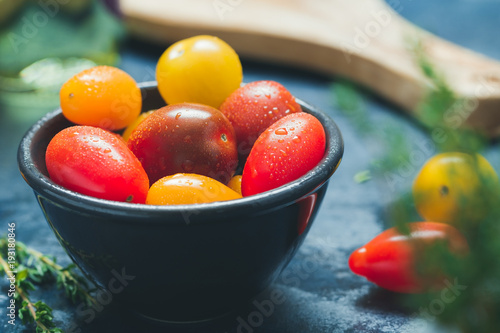 Colorful cherry tomatoes in a black bowl in a kitchen.