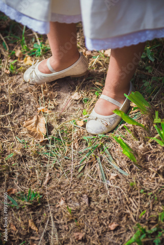 Girl's feet in earthy soil with wild grass.