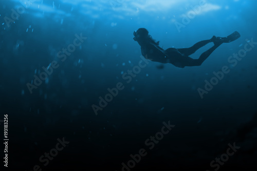 Fashionable and athletic girl diver alone in the depths of the ocean.
