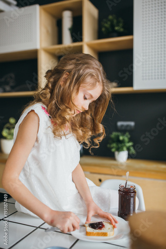 Little girl making breakfast on the table in the kitchen 