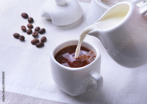 Cup of hot coffee espresso, coffee beans, jug of milk, and bowl with sugar on white background for copy space. Coffee concept.