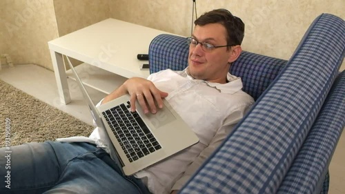 the man in glasses fell asleep while working in the laptop on his sofa in his city apartment photo