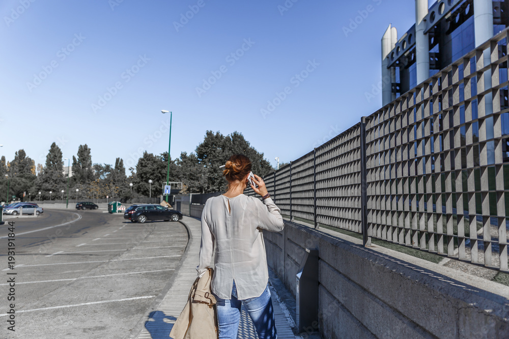 Business woman talking on her mobile phone, while walking down the street Business woman talking on her mobile phone, while walking down the street