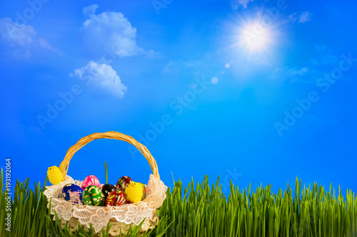 Basket with colorful easter eggs on green grass. Raster illustration.