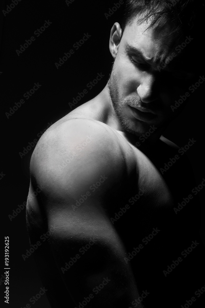 Big and strong muscular man in posing in a low light. Fitness model or a trainer showing his biceps, shoulders and chest. Angry mma fighter or a Bodybuilder is ready to kick ass. Big and strong muscular man in posing in a low light. Fitness model or a trainer showing his biceps, shoulders and chest. Angry mma fighter or a Bodybuilder is ready to kick ass.