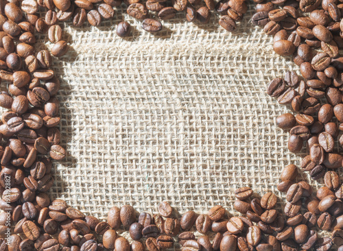 Golden coffee beans positioned as a frame on a hessian with an empty space for add or message