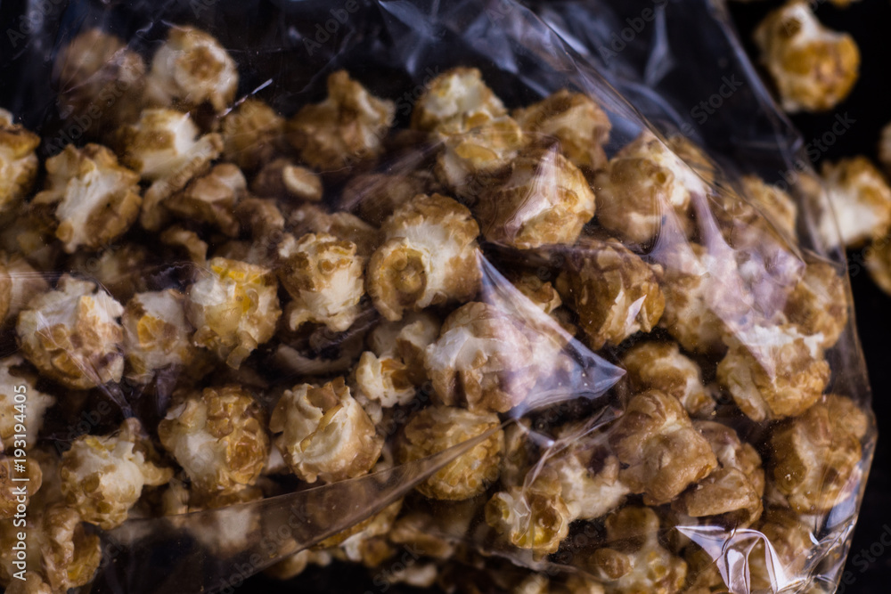 Sweet popcorn on the black background. Popcorn in the pink bucket. Snack for the movies. Cinema set. Sweet popcorn on the black background. Popcorn in the pink bucket. Snack for the movies. Cinema set.