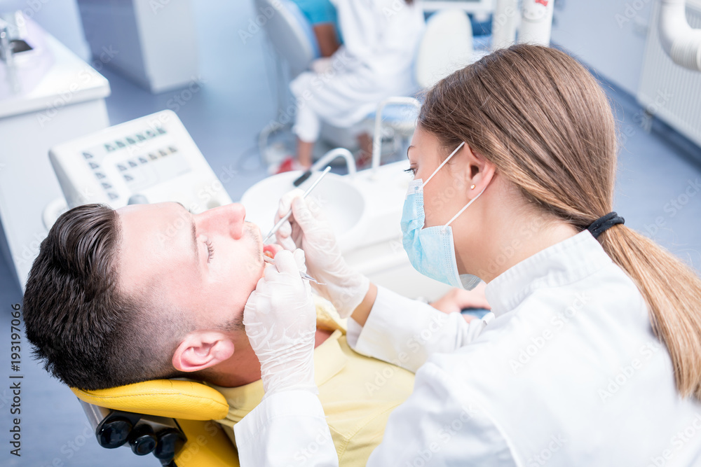 Obraz premium people, medicine, stomatology and health care concept - happy female dentist with mirror checking patient man teeth up at dental clinic office.