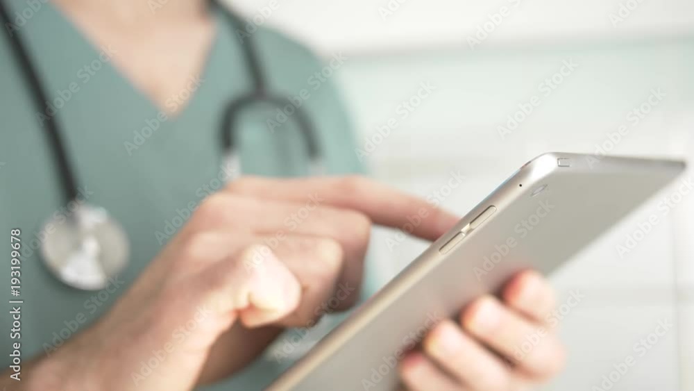 Doctor in uniform working with a digital tablet in his hand, making gestures on the screen. Doctor in uniform working with a digital tablet in his hand, making gestures on the screen.