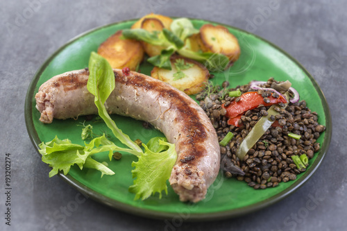 France Grilled Toulouse sausage with roasted potatoaes and salad and lentils on old wooden background photo