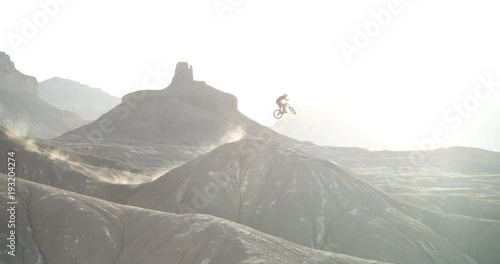Pan right, mountain biker goes off jump in Utah