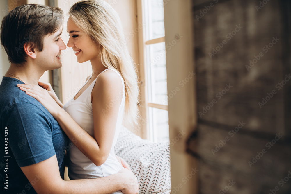 Naklejka premium Amazing happy couple hugging near the window. They are happy spending time together