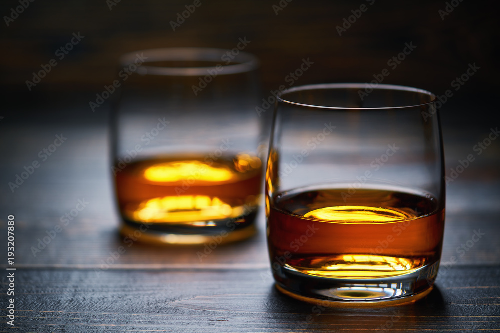 Two glasses of old whiskey on wooden table