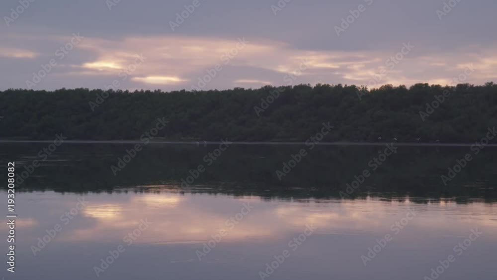 Flock of birds fly over water during sunset Flock of birds fly over water during sunset