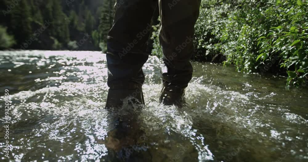 Fisherman in fishing boots walks in water, slow motion Fisherman in fishing boots walks in water, slow motion