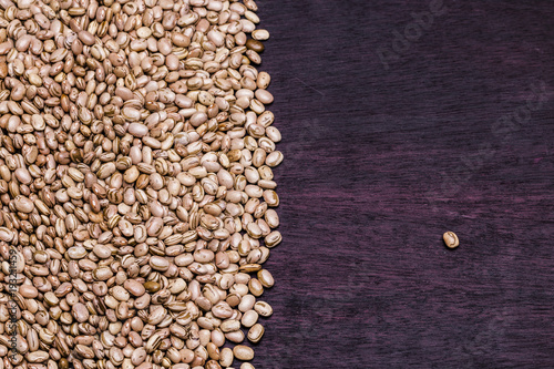 Carioca beans grains on the left side of the frame and a single bean on the right on a purple wooden table / Feijão Carioca
 photo