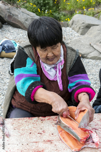 Senior Chukchi woman cuts  just catched sallmon on the sea shore and prepared it for drying