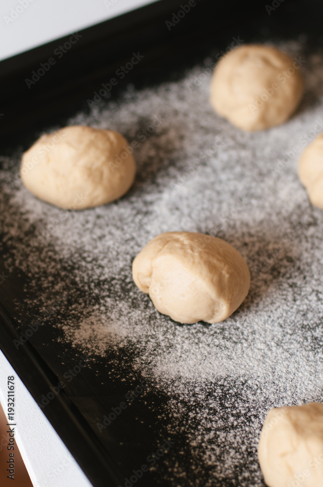 Unbaked, rolled traditional German Kaiser rolls or Austrian Vienna rolls homemade from yeast dough with white wheat flour on flour dusted baking sheet before final rise and before baking