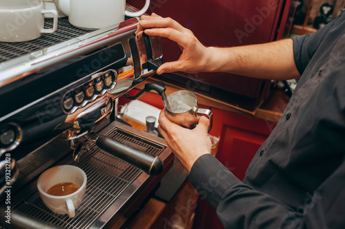 Barista makes coffees in bar. Latte preparation in coffee machine. Hands bartender cooking coffee, preparation milk for latte coffee. Horizontally framed shot.