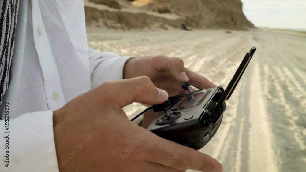 Closeup of a man using a drone controller with his hands while on a sandy beach. Closeup of a man using a drone controller with his hands while on a sandy beach.