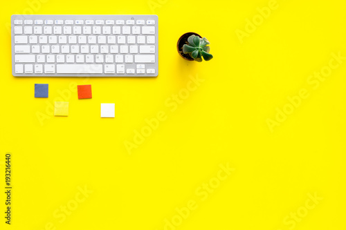 Minimalistic office desk with plant. Yellow background top view copy space
