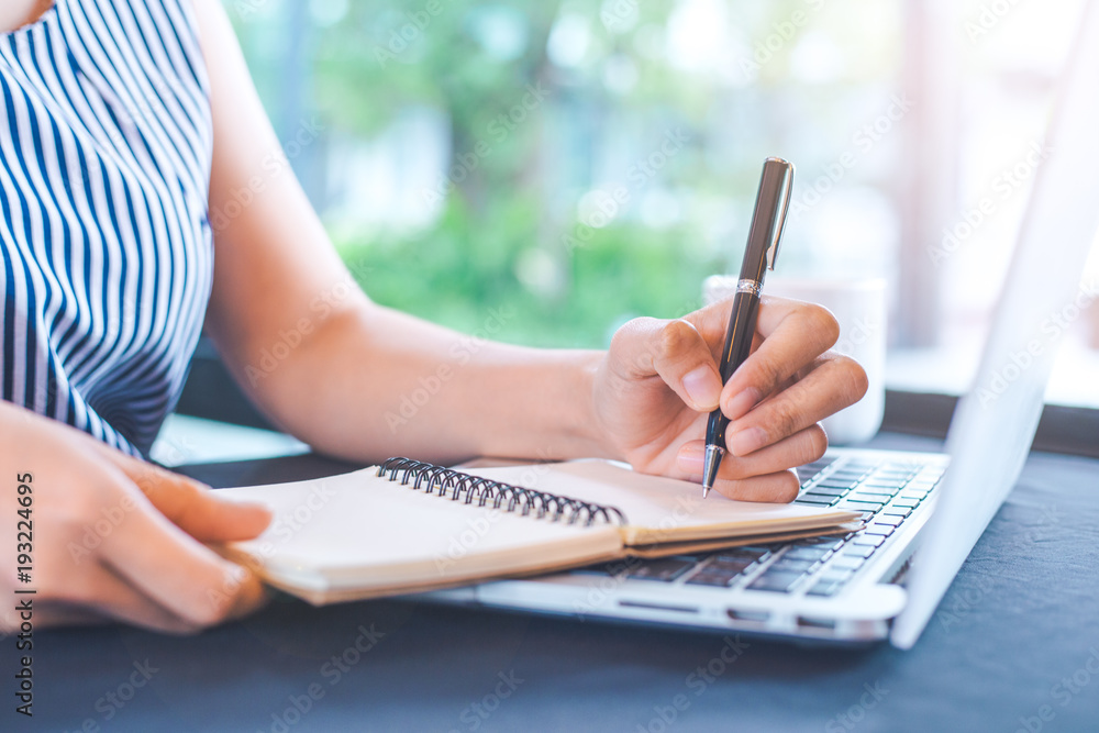 Woman hand writing on notepad with a pen in the office.