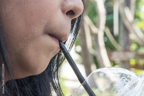 Close up of a girl drinking a water from straw in the hot time., hungry or thirsty concept