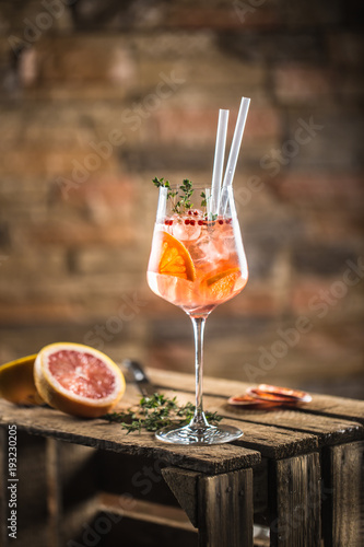 Cocktail drink on a old  wooden board. Alcoholic beverage with tropical fruits red pepper herb and ice