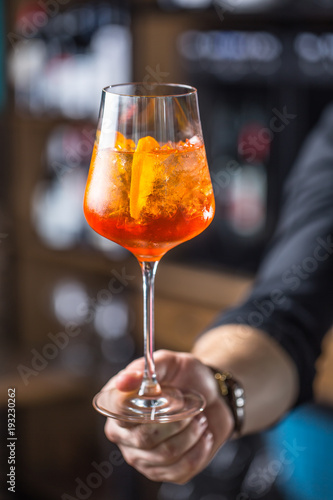Aperol spritz drink. Bartender hand holding glass with  Aperol Spritz drink.