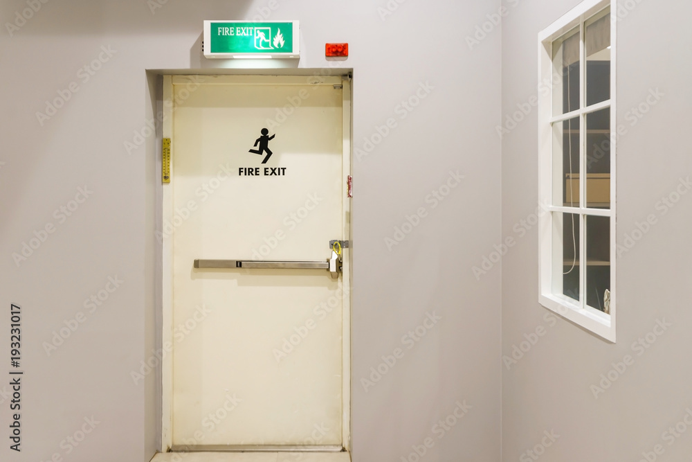 Naklejka premium Building emergency exit with exit sign on door and fire extinguisher on the outside of a building