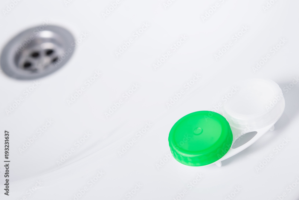 a container for storage of lenses lies in a white washbasin a container for storage of lenses lies in a white washbasin