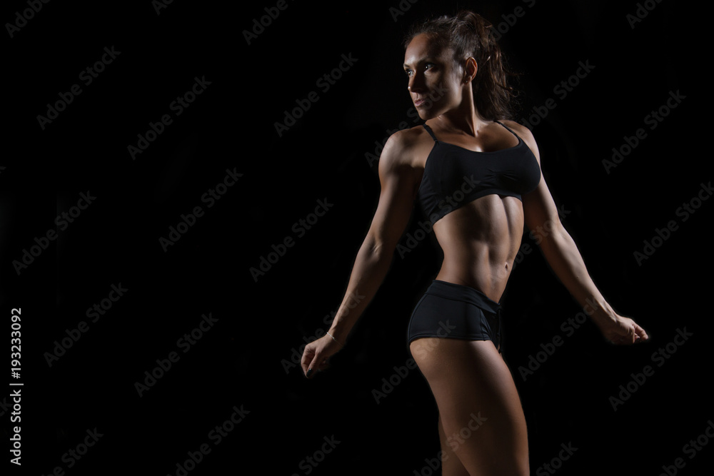 Fit woman posing on black background