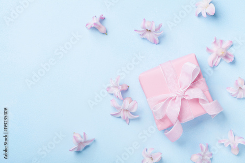 Pink flowers and present or gift box on blue pastel table top view. Greeting card for 8 March, Womans or Mothers Day. Flat lay. © juliasudnitskaya