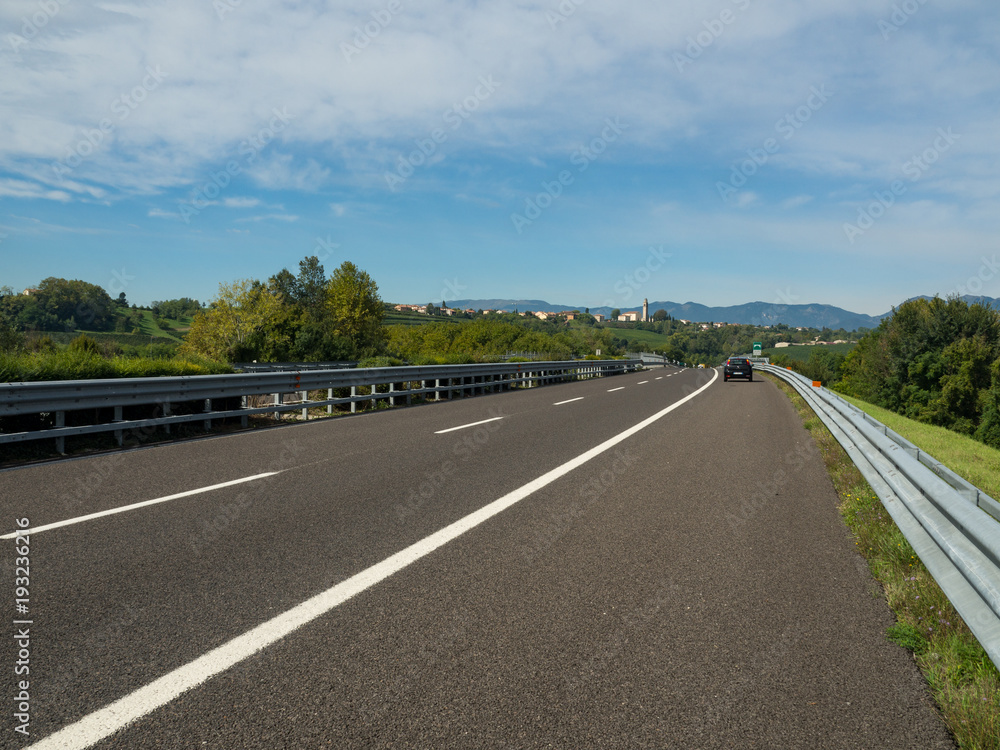 Fototapeta premium Asphalt road in Italy, Alps in a beautiful summer day, green grass, Dolomiti alps. September, 2017.