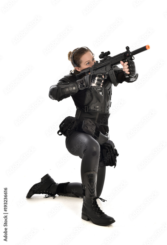 full length portrait of female wearing black tactical armour, crouching pose holding a weapon, isolated on white studio background. full length portrait of female wearing black tactical armour, crouching pose holding a weapon, isolated on white studio background.