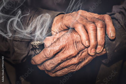 old hands holding the pipe with smoke