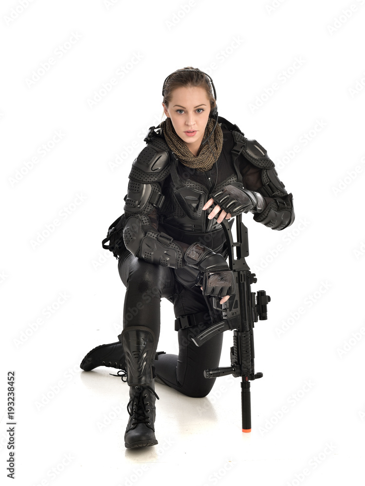 full length portrait of female wearing black tactical armour, crouching pose holding a weapon, isolated on white studio background. full length portrait of female wearing black tactical armour, crouching pose holding a weapon, isolated on white studio background.