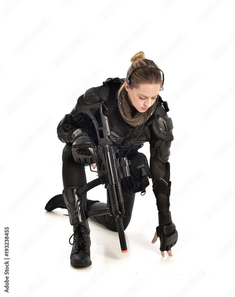 full length portrait of female wearing black tactical armour, crouching pose holding a weapon, isolated on white studio background. full length portrait of female wearing black tactical armour, crouching pose holding a weapon, isolated on white studio background.