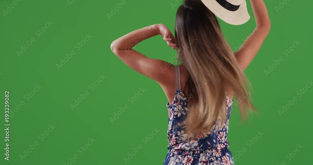 Rear view of young woman taking off hat and letting down hair on