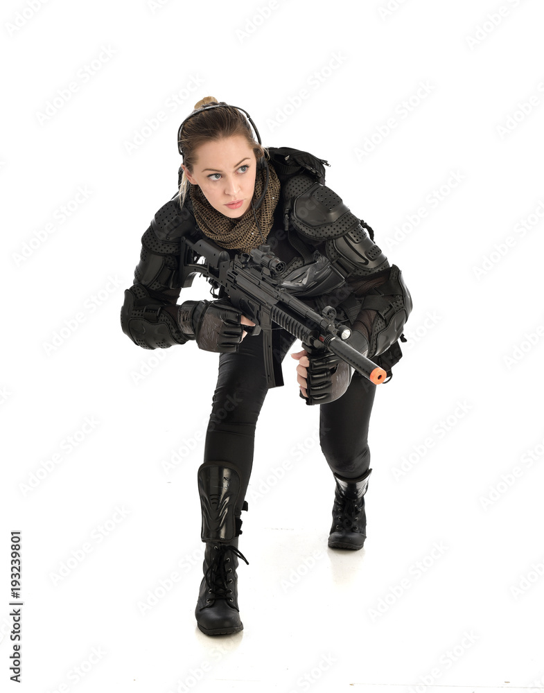 full length portrait of female wearing black tactical armour, crouching pose holding a weapon, isolated on white studio background. full length portrait of female wearing black tactical armour, crouching pose holding a weapon, isolated on white studio background.