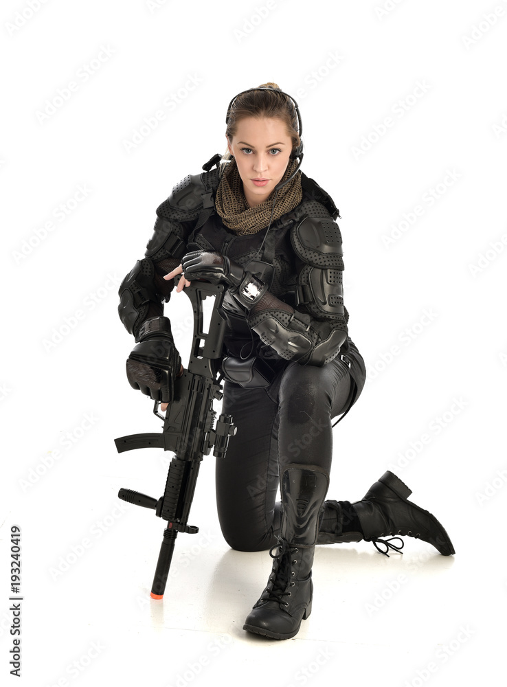 full length portrait of female wearing black tactical armour, crouching pose holding a weapon, isolated on white studio background. full length portrait of female wearing black tactical armour, crouching pose holding a weapon, isolated on white studio background.