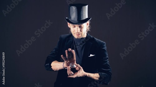 Magician is making a sparkling crystal disappear from his right fist and taking from the air.